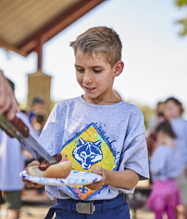 Cub Scouts at the lake - boy getting a hotdog from the grill; lunch; dinner; eating; grilling; picnic in pavilion; food